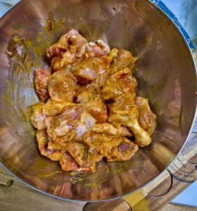 Raw chicken pieces marinated with turmeric, red chili powder, salt, and ginger garlic paste.
